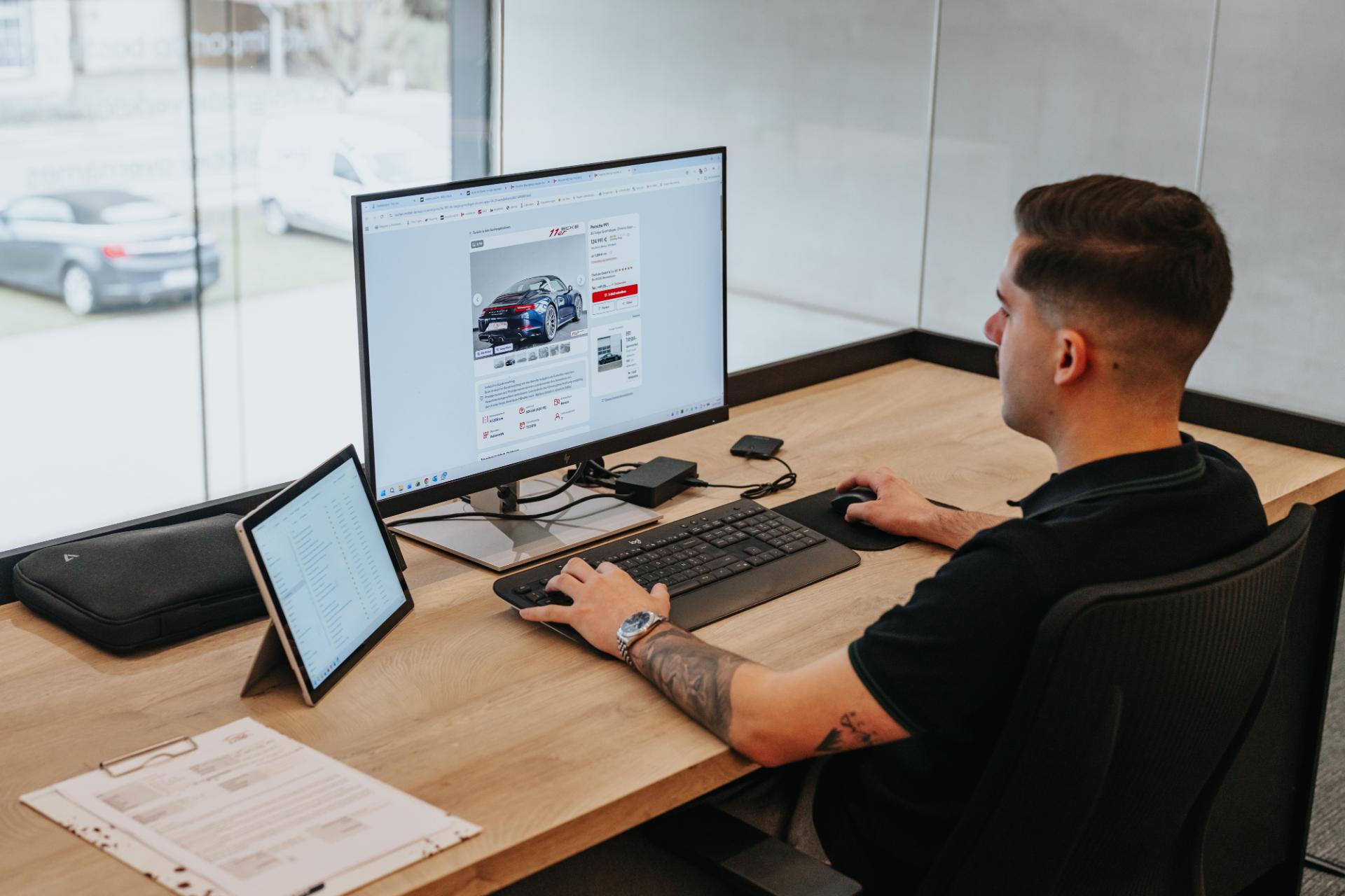 Medewerker beheert auto listing en website op computer